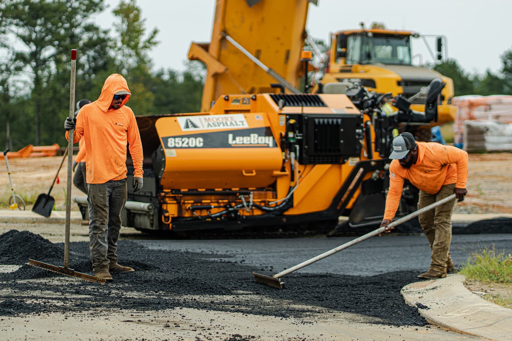Moore Asphalt crew spreading fresh asphalt around a paver
