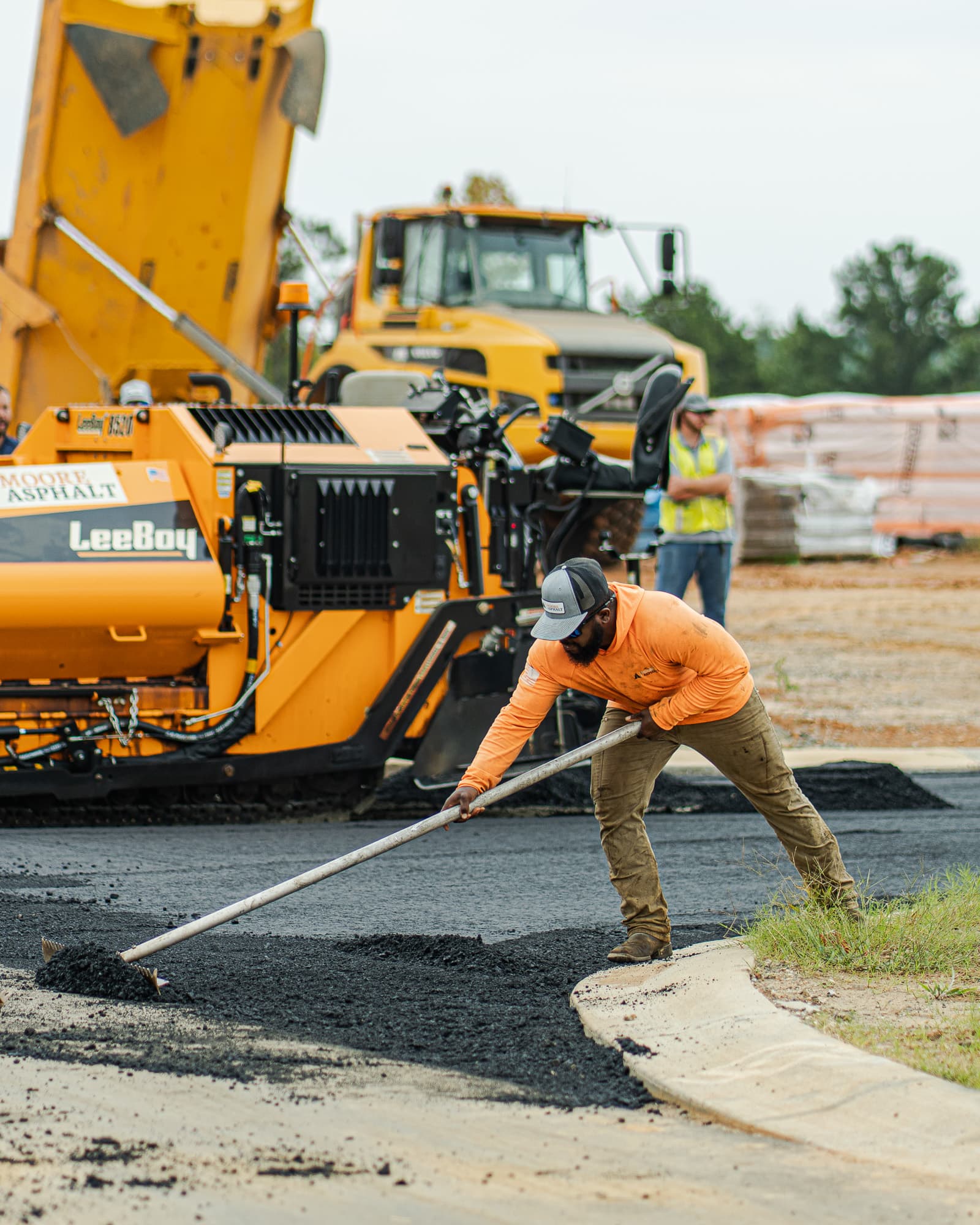 Moore Asphalt crew shaping fresh asphalt along a curb