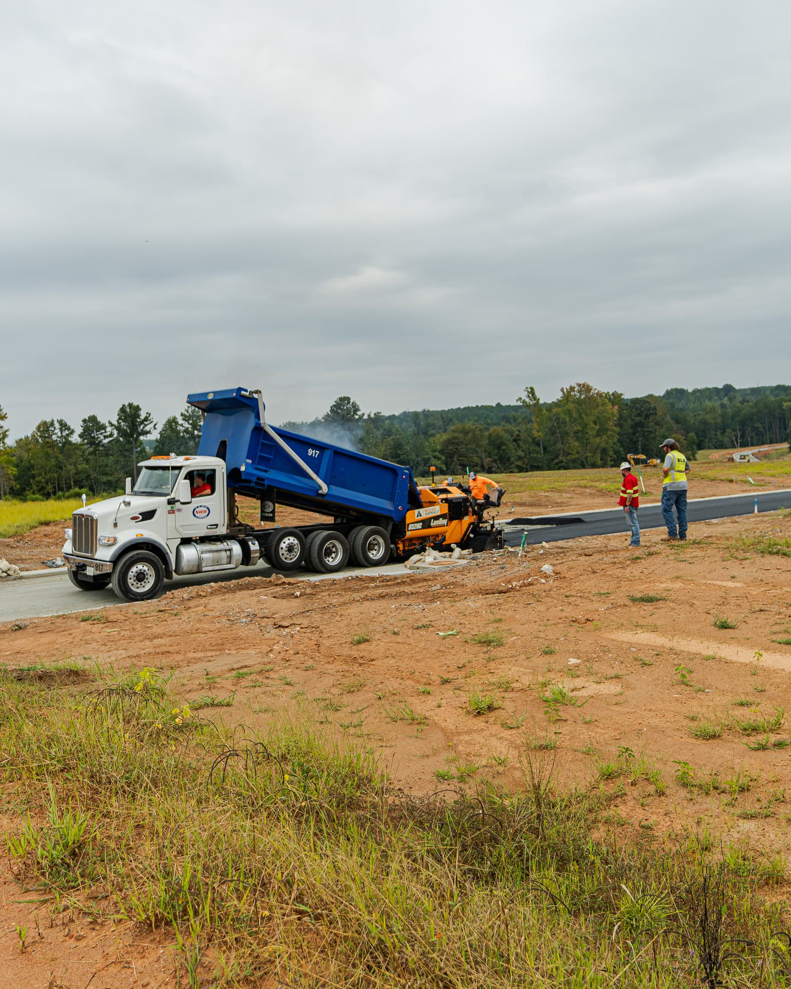 Dump truck feeding asphalt into the paver on a new road